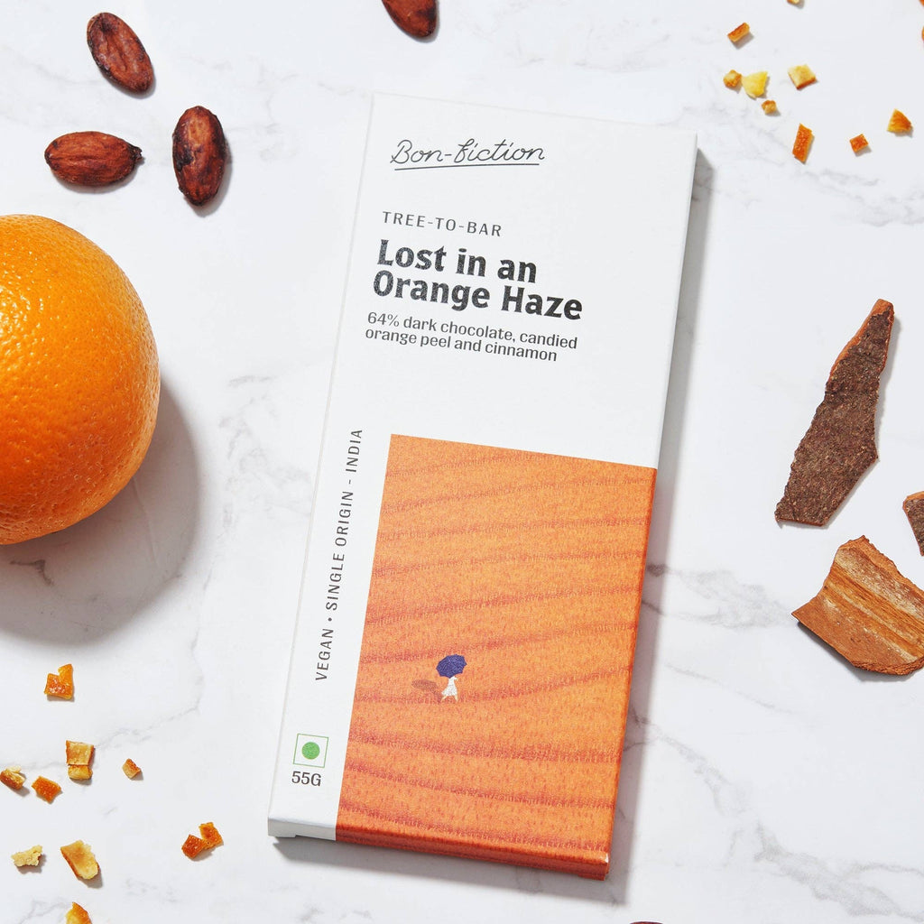 The front of a wrapped "Lost in an Orange Haze" bar from Bon Fiction on a marble table with ingredients