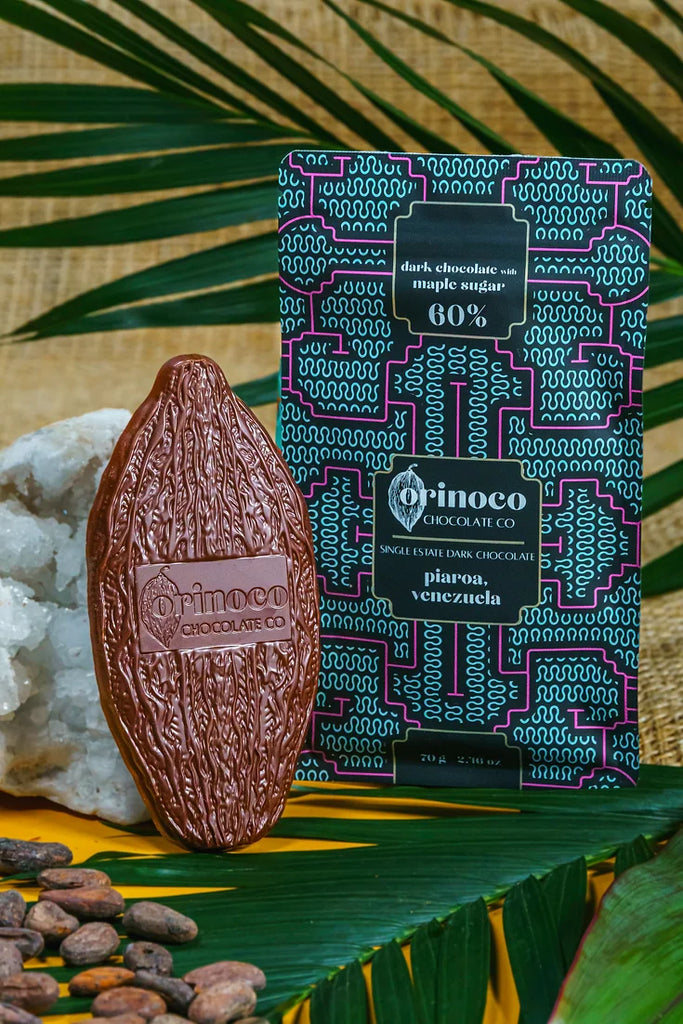 Piaroa, Venezuela 60% Dark Chocolate on a table with a crystal, cocoa beans, and leaves