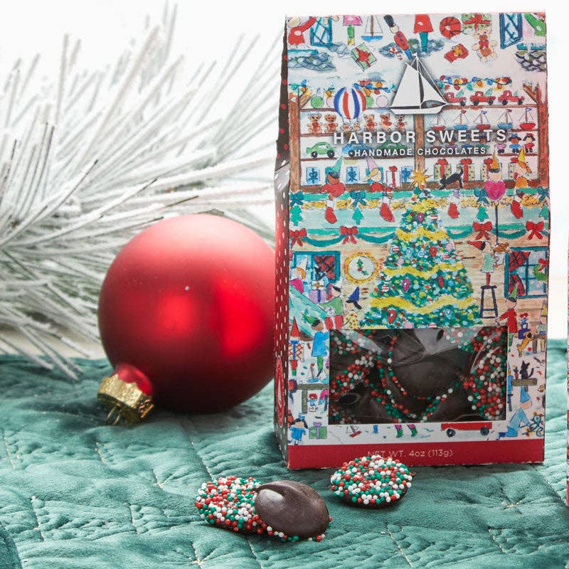 Holiday Sprinkled Dark Chocolate Nonpareils on a blue table with a Christmas tree ornament