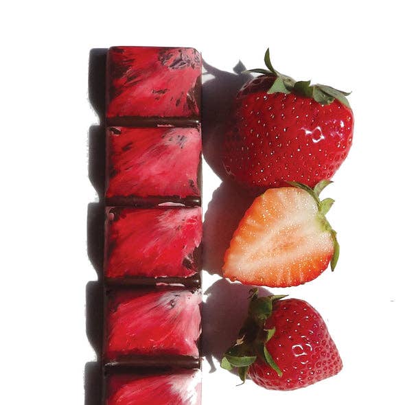 Unwrapped Strawberry Balsamic Dark Chocolate Truffles with strawberries to the right, against a white background.